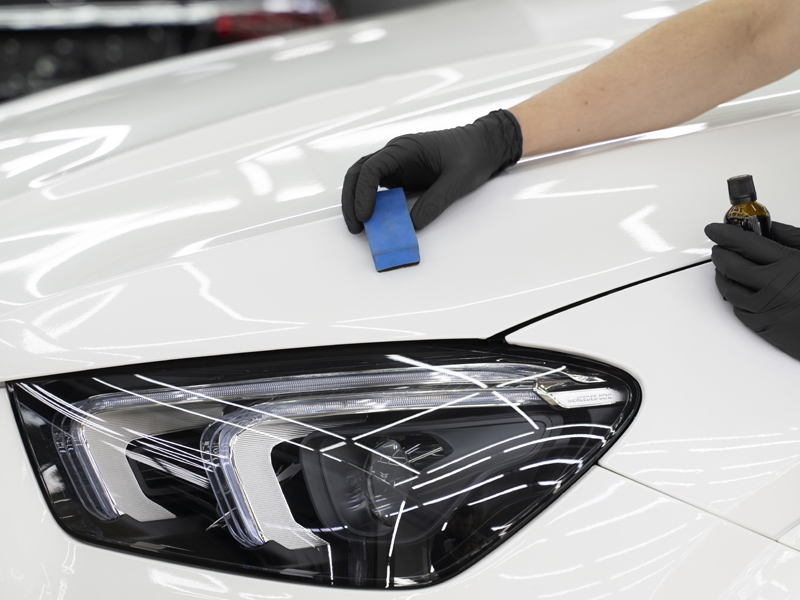 Technician applying nano ceramic coating to a white car