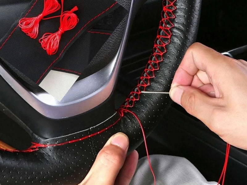 Hand stitching a red-thread leather steering wheel cover